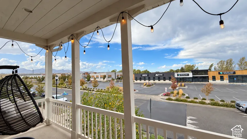 Covered balcony featuring string lighting and white railings