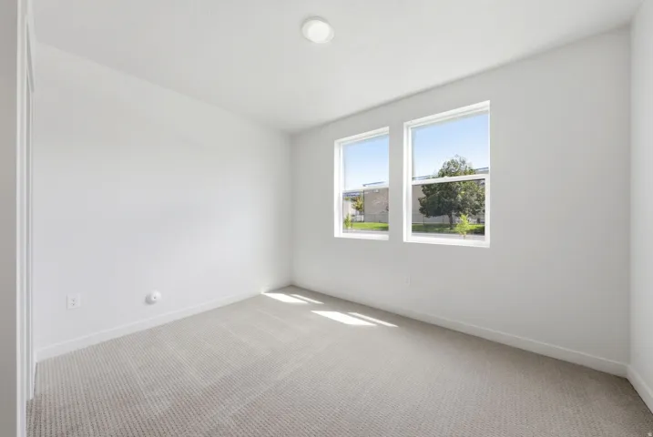 Recessed ceiling light, two windows, wall-to-wall carpeting, and white wall finishes