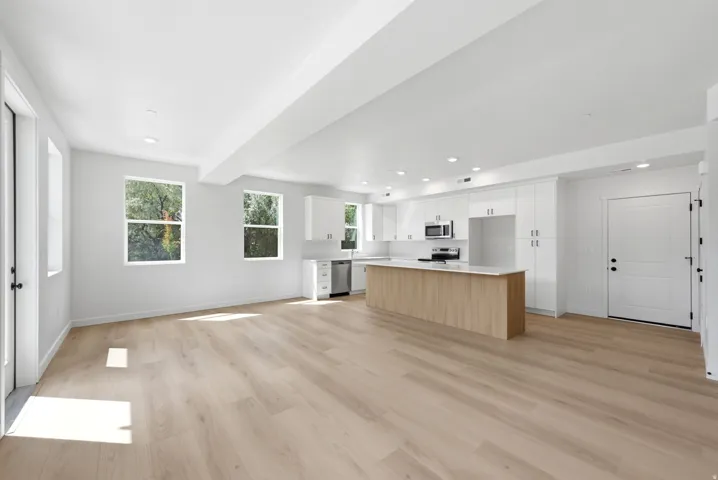Open-concept living space with wood-finish flooring, recessed lighting, and white walls