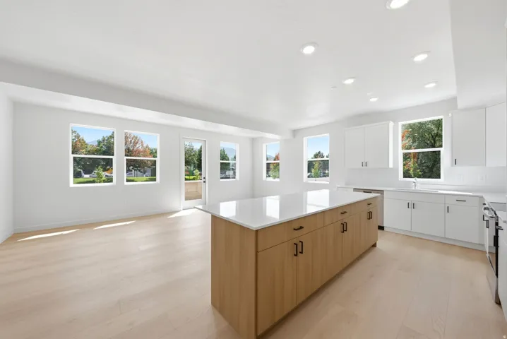 Open-concept kitchen and living area featuring a large center island with wood-finish cabinetry, white countertops, and recessed lighting