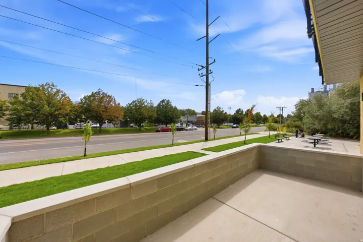 Concrete patio with a block wall, sidewalk, and adjacent green spaces