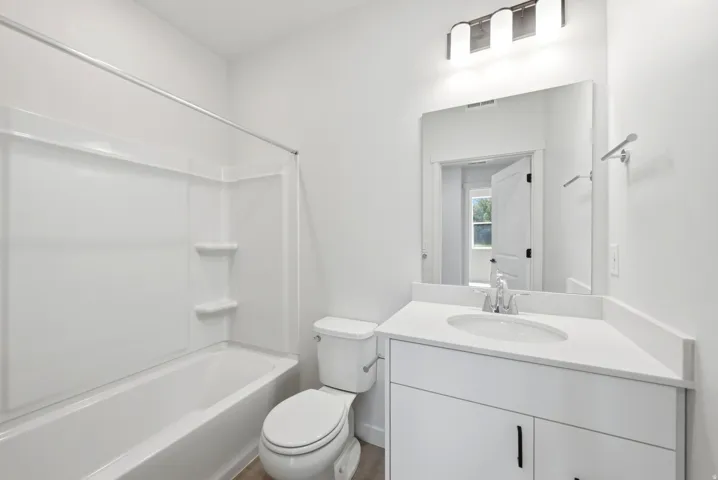 White vanity with a single basin sink, white countertop, and brushed nickel faucet
