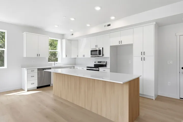 Contemporary kitchen with light wood-finish flooring, white cabinetry, recessed lighting, and stainless steel appliances
