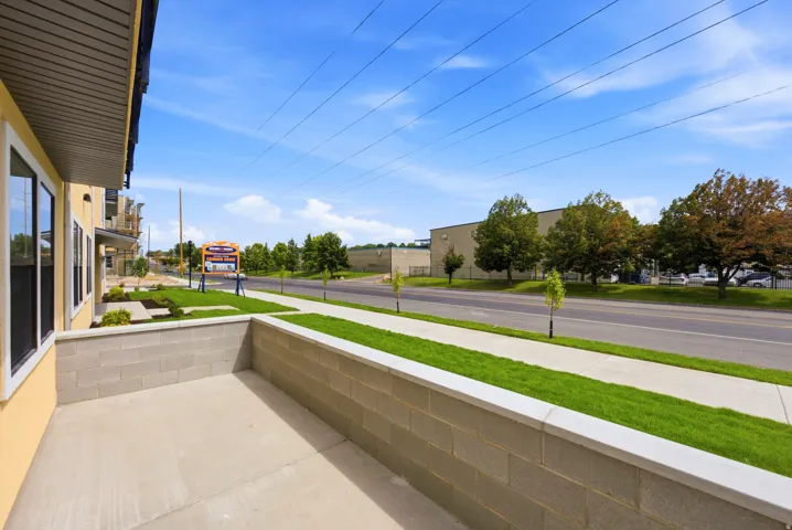 Concrete patio with block wall, adjacent to a manicured lawn and sidewalk