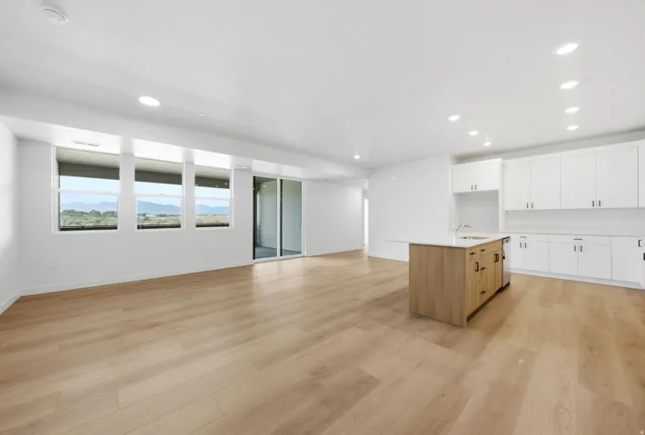 Wood-finish flooring throughout, featuring a kitchen island with built-in sink and white cabinetry