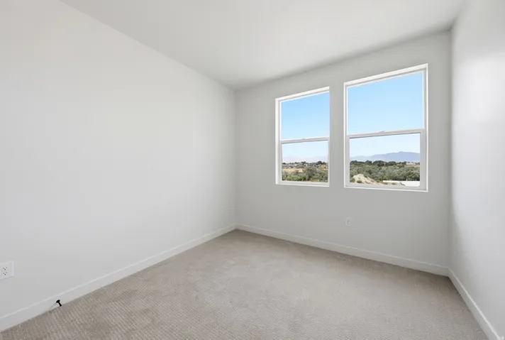Light-filled room featuring two windows, neutral wall tones, and carpeted flooring