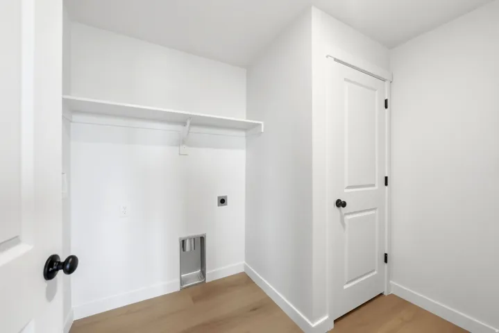 Dedicated laundry area featuring a built-in shelf, plumbing hookups, electrical outlet, and wood-finish flooring