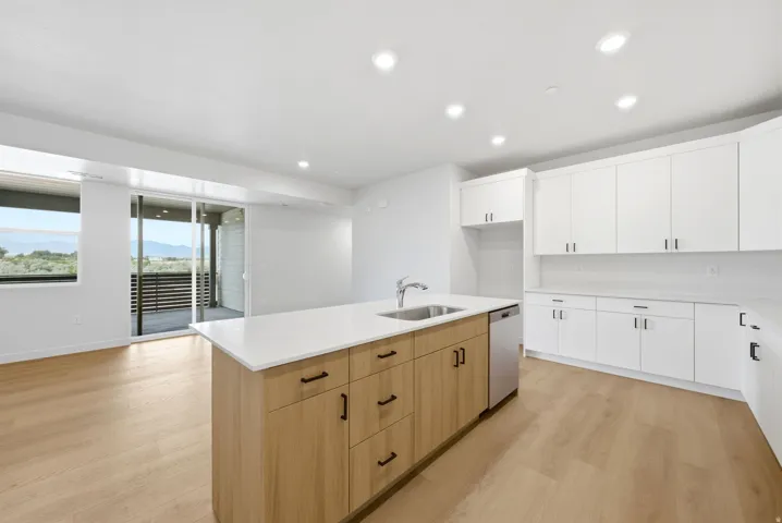 Kitchen featuring a central island with wood-finish cabinetry, white countertops, and a stainless steel sink