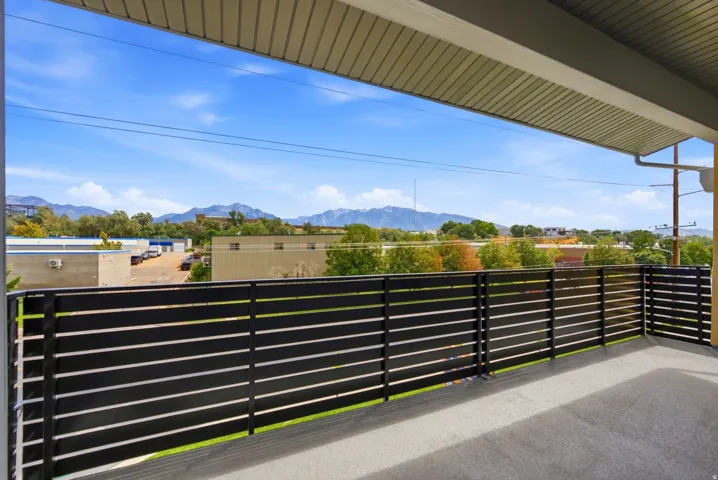 Expansive outdoor balcony with a black slatted railing, providing a broad mountain backdrop