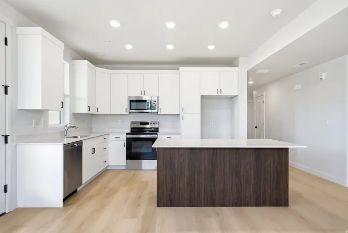 Contemporary kitchen with white cabinetry, stainless steel appliances, a wood-finish island, and recessed lighting