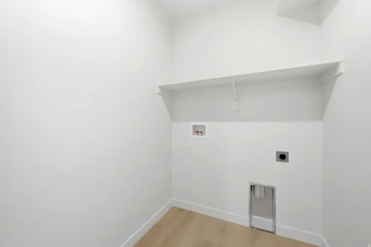 Utility area with wood-finish flooring, a wall-mounted shelf, and appliance hookups