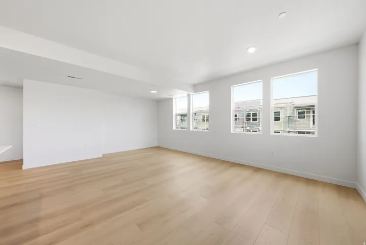 Light wood-finish flooring, white walls, multiple large windows, and recessed lighting