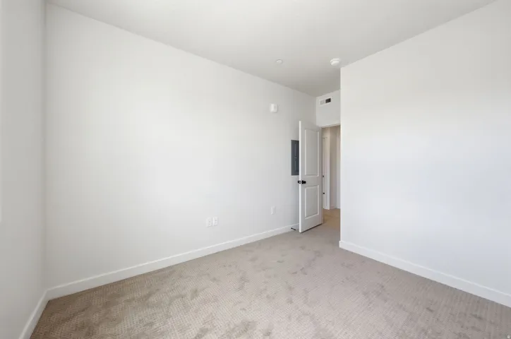 Neutral tone wall color, recessed ceiling lighting, textured carpeting, and white trim
