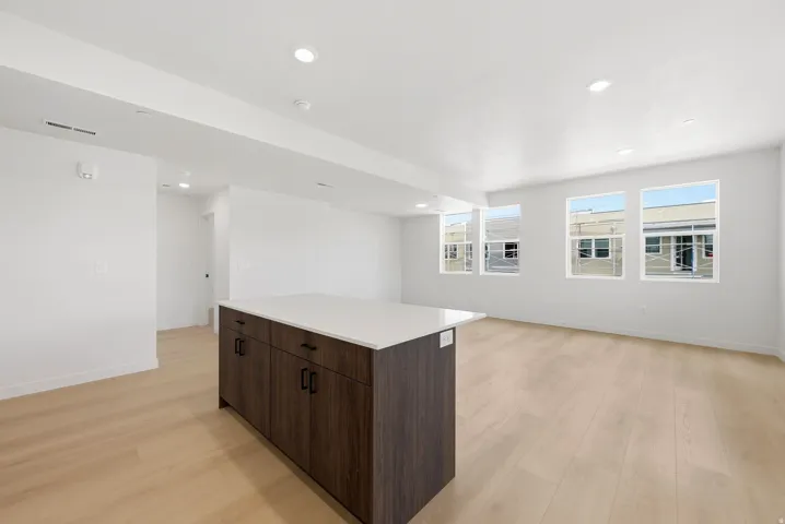 Open-concept living area featuring light wood-finish flooring, recessed lighting, and an expansive wall with multiple windows