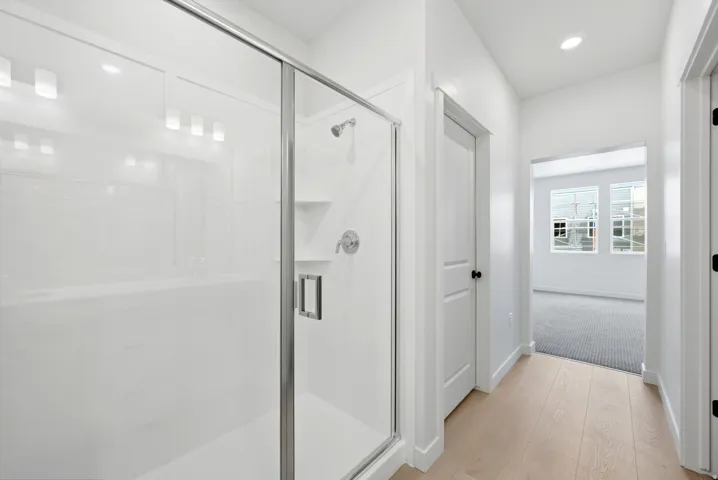 Glass-enclosed shower with built-in shelving, chrome fixtures, and overhead lighting