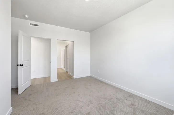 Neutral-toned carpeting, white walls, and white trim throughout