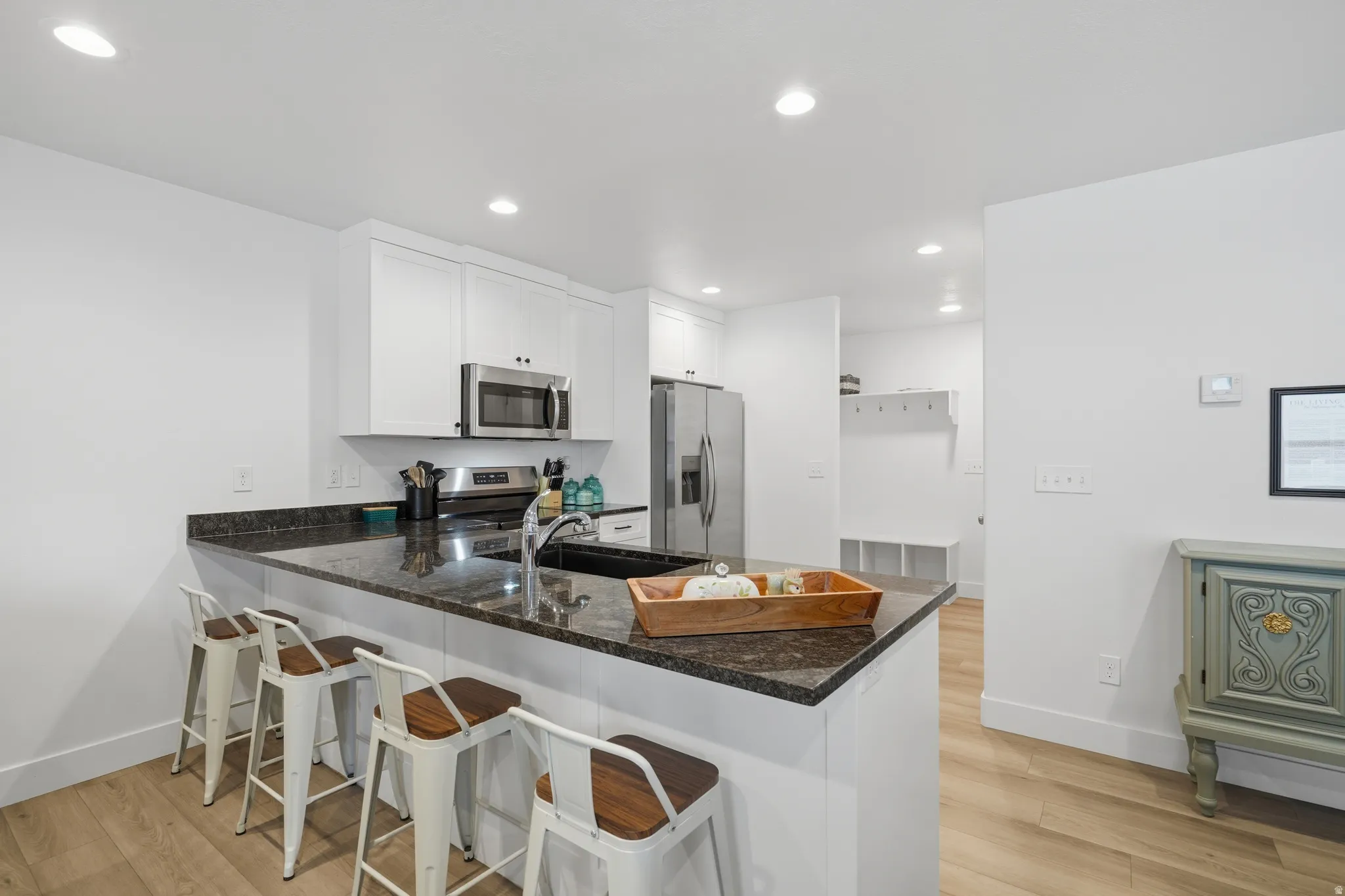 Kitchen island with a dark stone countertop, undermount sink, and stainless steel faucet