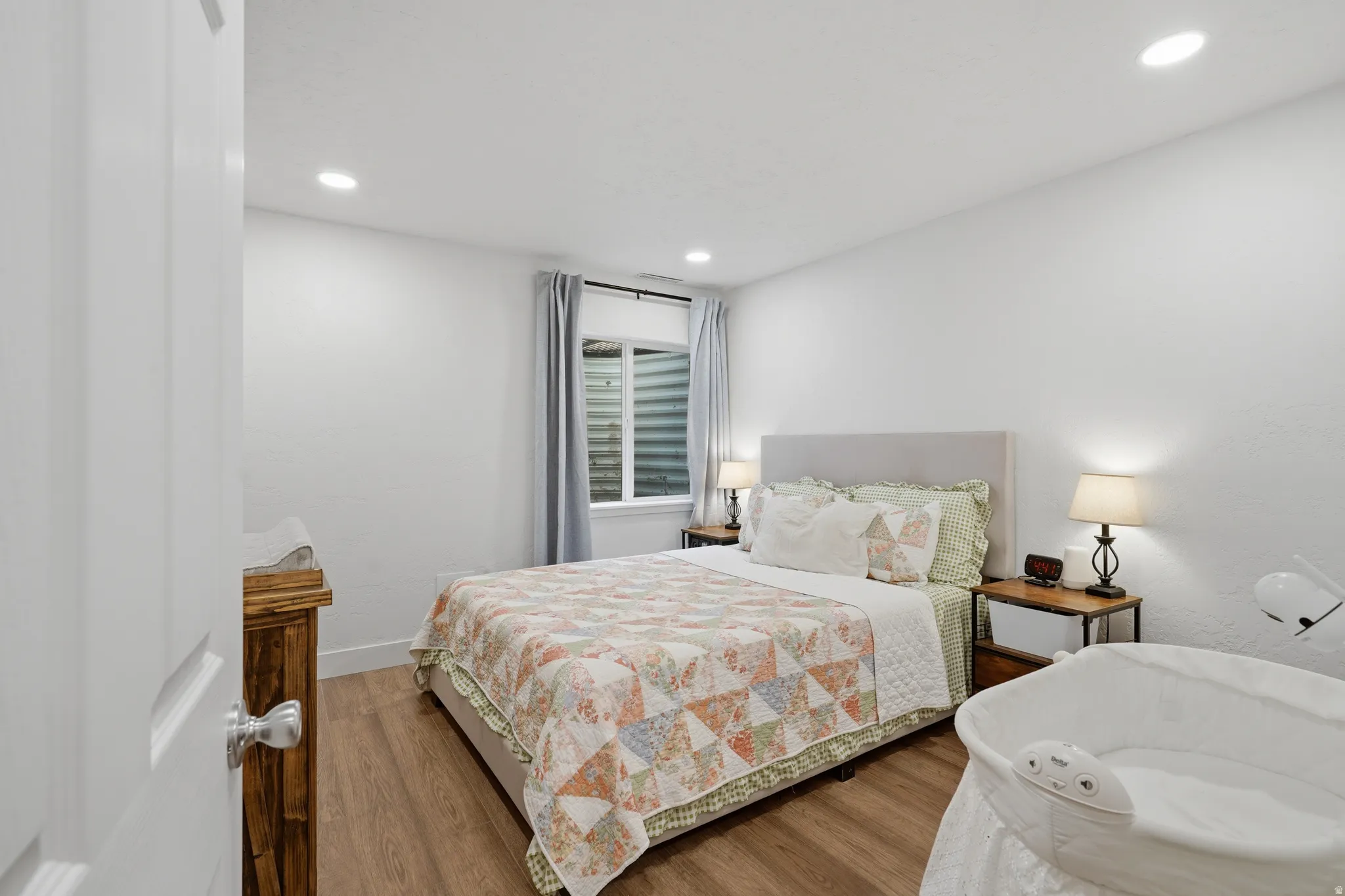 Recessed ceiling lighting, light wood-finish flooring, white walls, and a light-colored window treatment