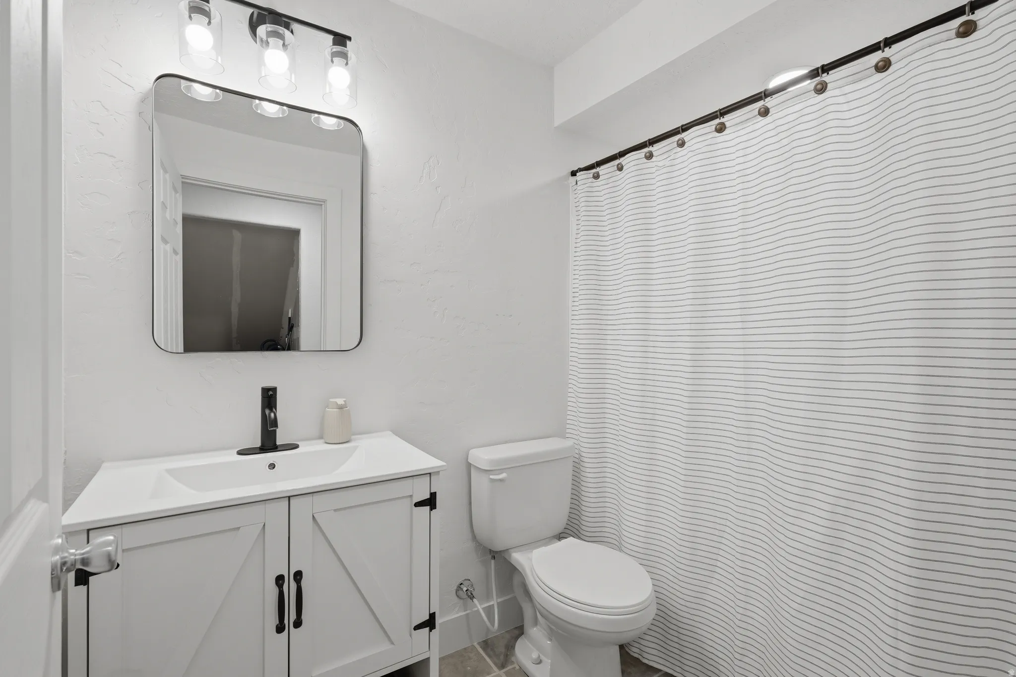 White vanity with barn door style cabinetry, black hardware, and integrated sink