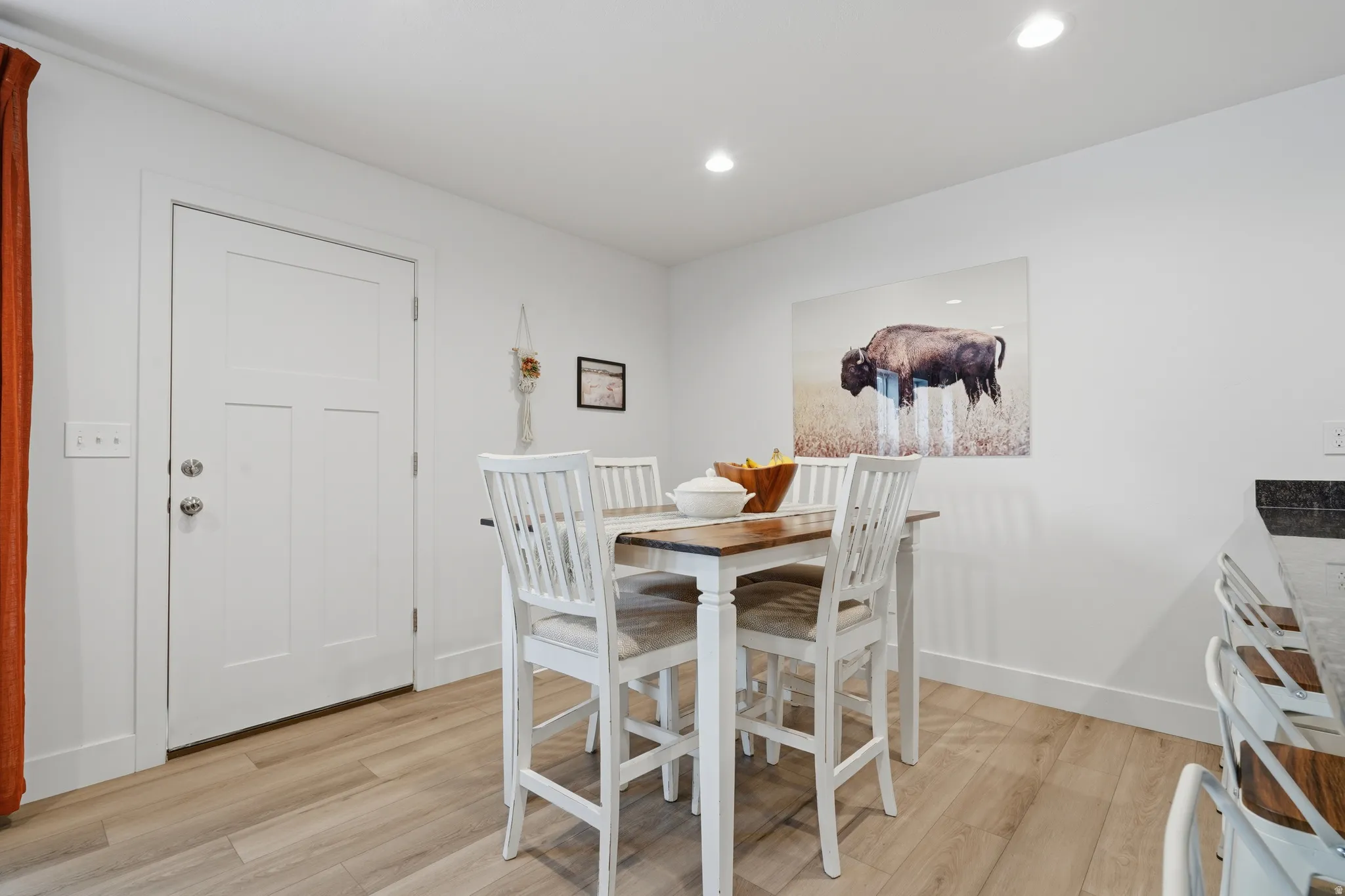 White interior door, wood-finish flooring, white walls, and recessed lighting