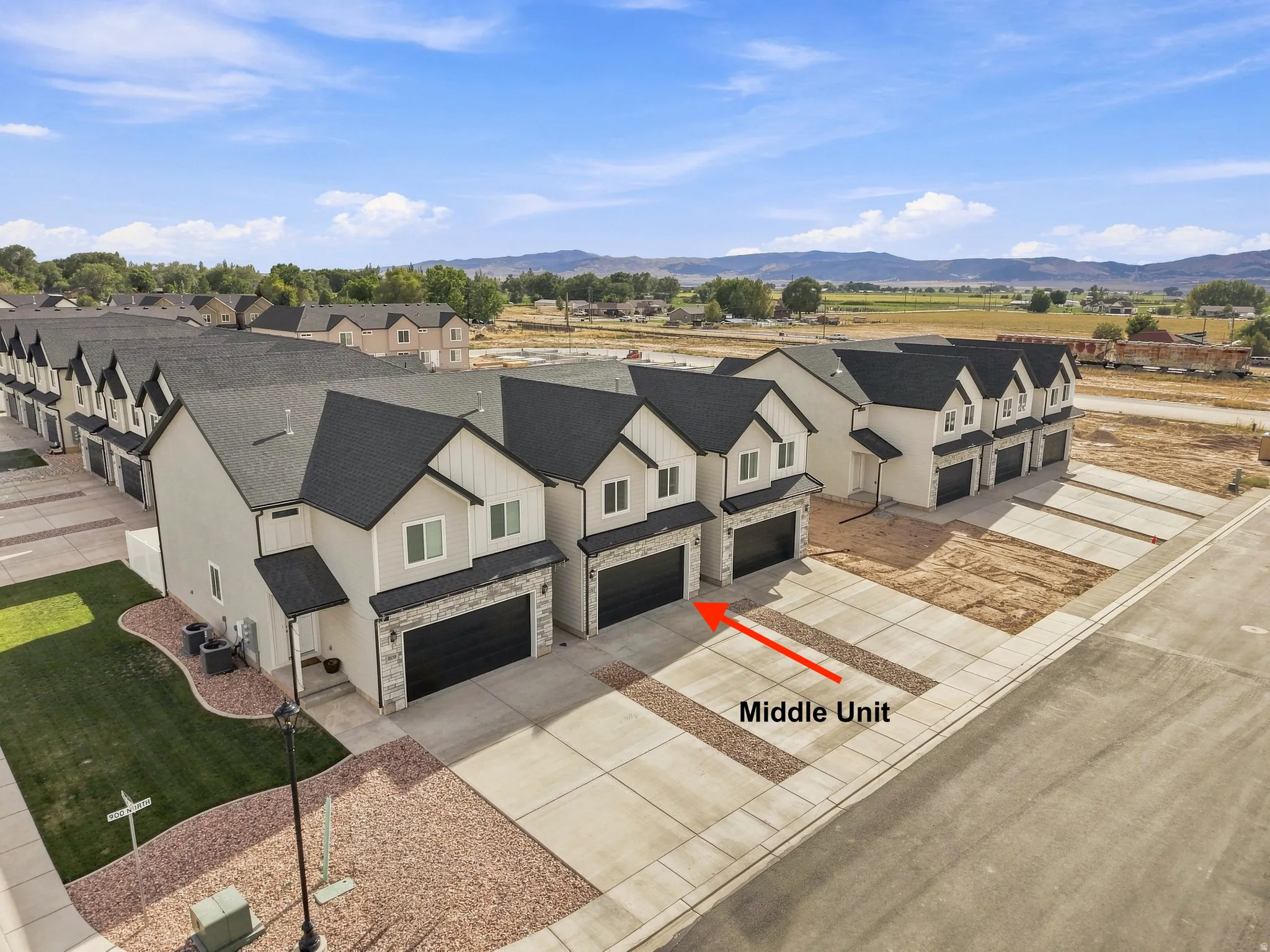 Modern townhome with attached garage, contrasting black roof, and light-toned siding