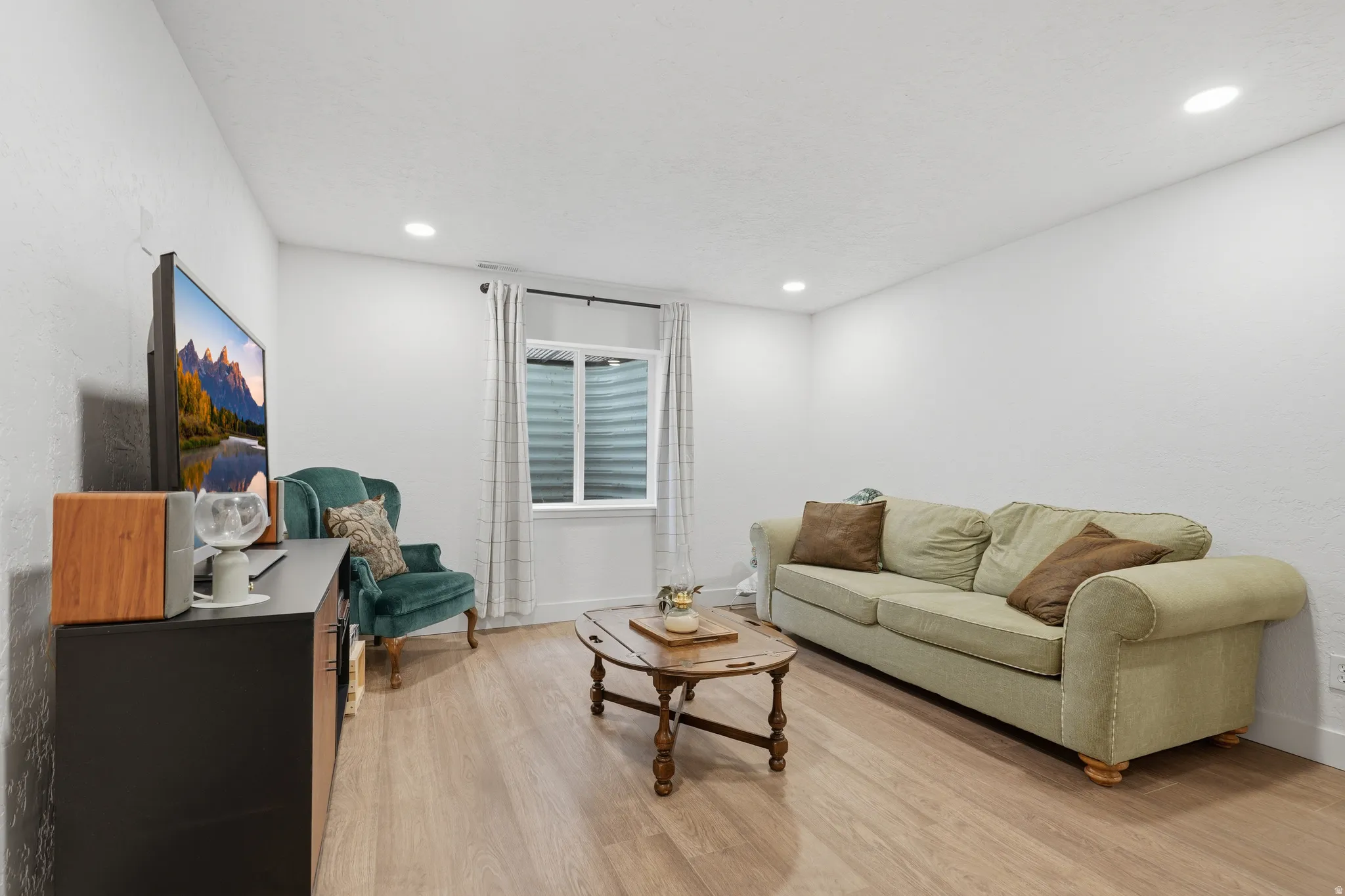 Light wood-finish flooring, recessed ceiling lighting, and a window with blinds