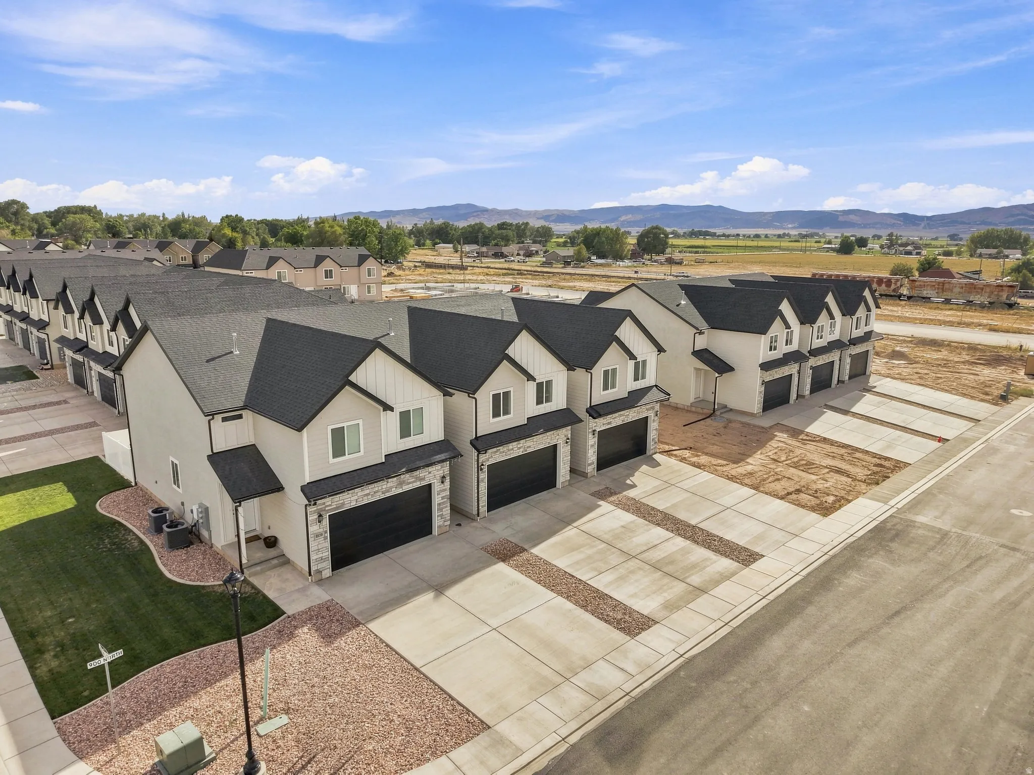 Newly constructed townhome community with modern exterior finishes, attached garages, and concrete driveways