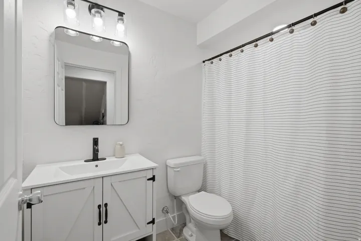 White vanity with barn door style cabinetry, black hardware, and integrated sink