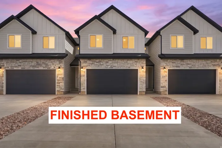 Contemporary townhome exterior featuring stone accents, dark garage doors, and a concrete driveway