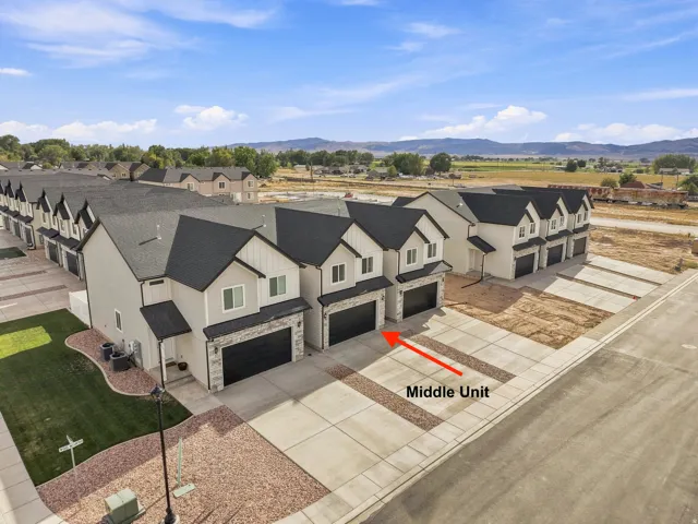 Modern townhome with attached garage, contrasting black roof, and light-toned siding