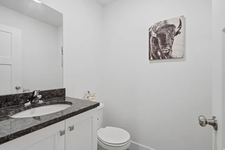 White vanity with storage, integrated sink, dark mottled countertop, and chrome faucet