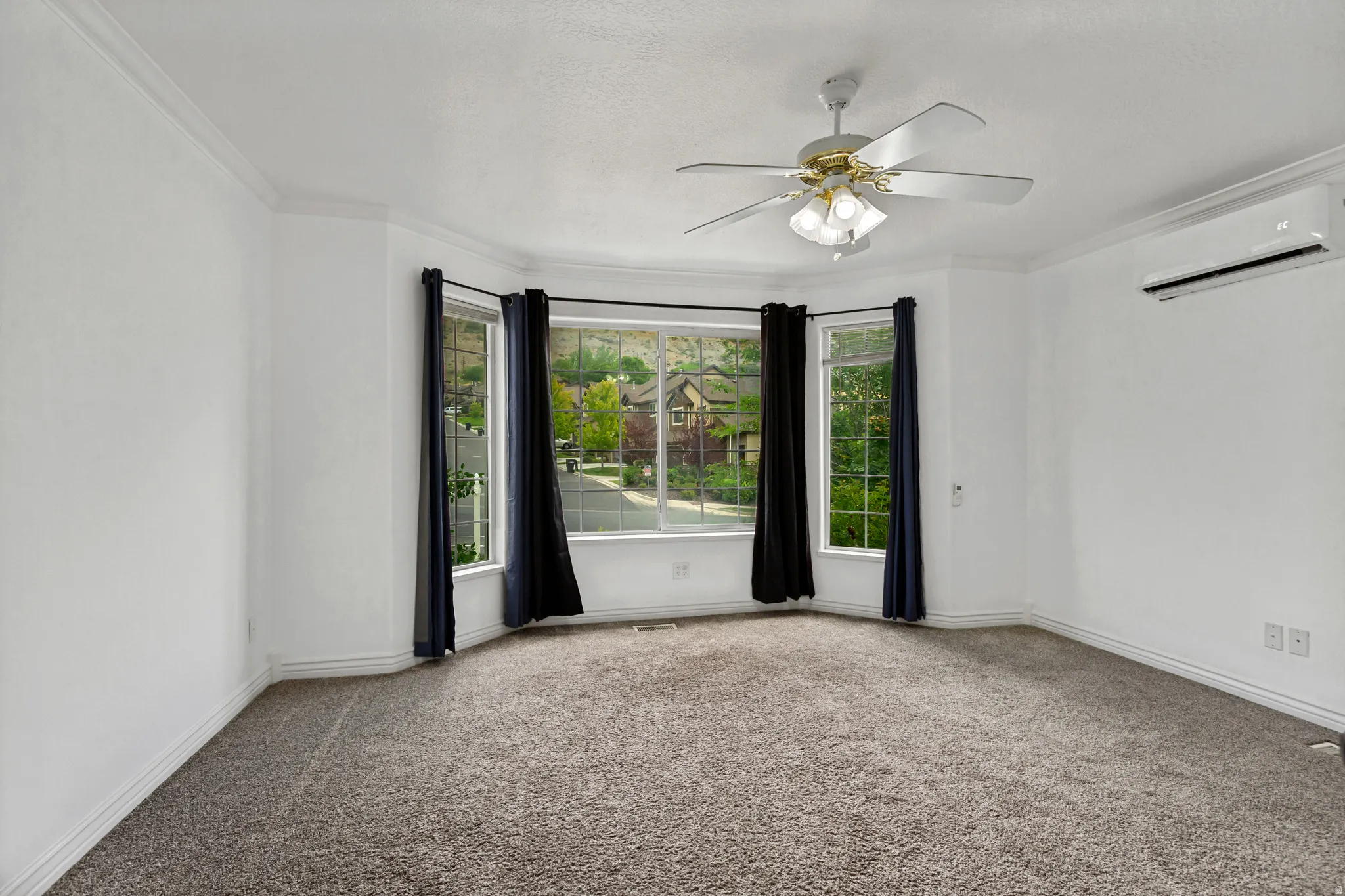 Bay window with multiple panes, ceiling fan, and wall-mounted climate control unit