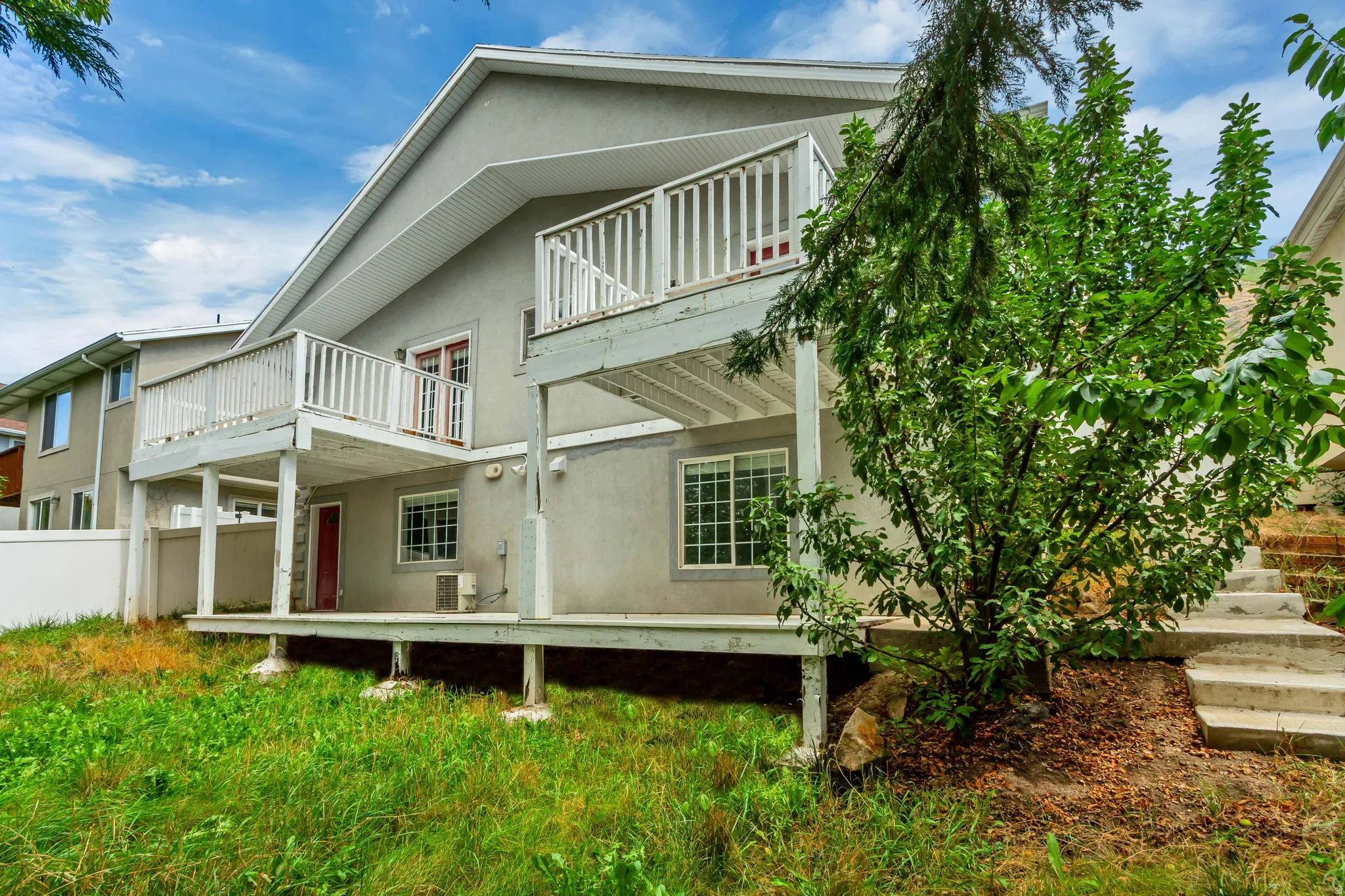 Exterior featuring a two-story deck, ground-level patio, and concrete staircase
