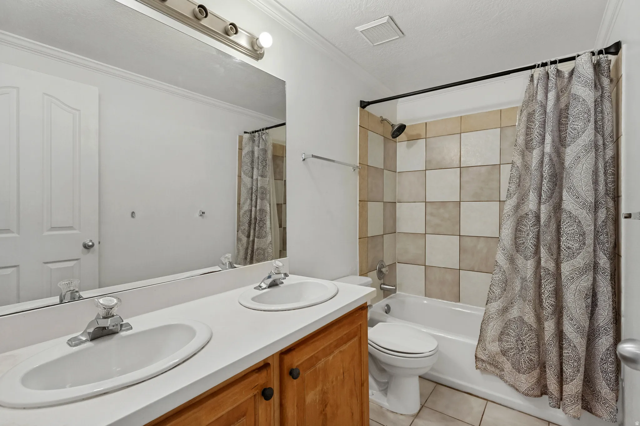Dual vanity with integrated sinks, wood-finish cabinetry, built-in mirror, and overhead strip lighting
