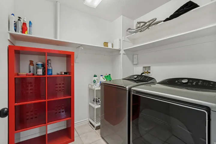 White walls and ceiling, two wall-mounted shelves, and tiled flooring
