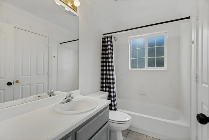 Bathroom featuring a built-in vanity with an integrated sink, a white bathtub with a shower, and a window with privacy glass