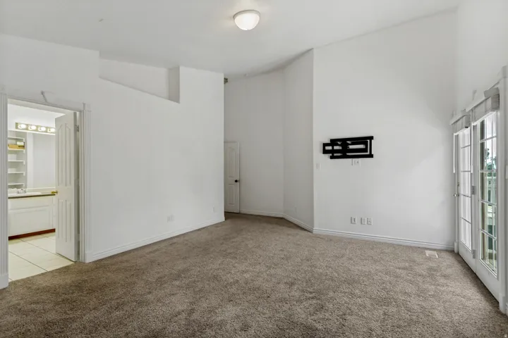 Spacious carpeted room with neutral wall finishes, recessed ceiling lighting, and multiple windows providing natural light