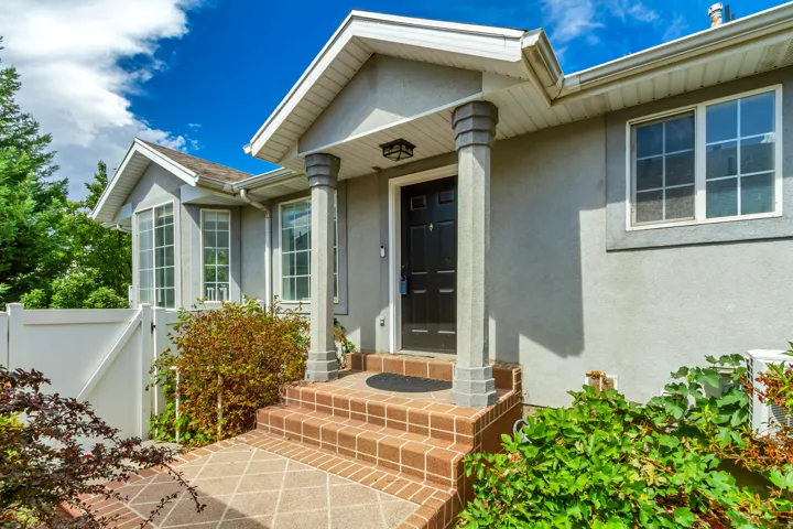 Stucco exterior with a covered entry, decorative columns, and a paneled front door