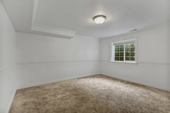 Recessed ceiling section, ceiling-mounted light fixture, window with grid panes, textured white walls, and neutral-toned carpeting