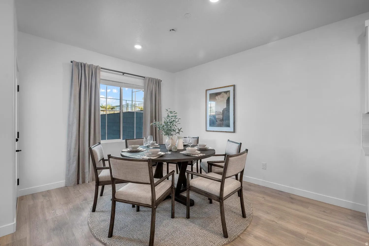 Recessed lighting, wood-finish flooring, and a large window with privacy blinds