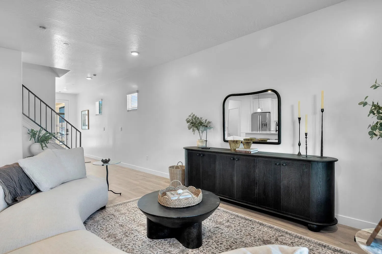 White interior walls, wood-finish flooring, recessed ceiling lighting, and a black metal handrail