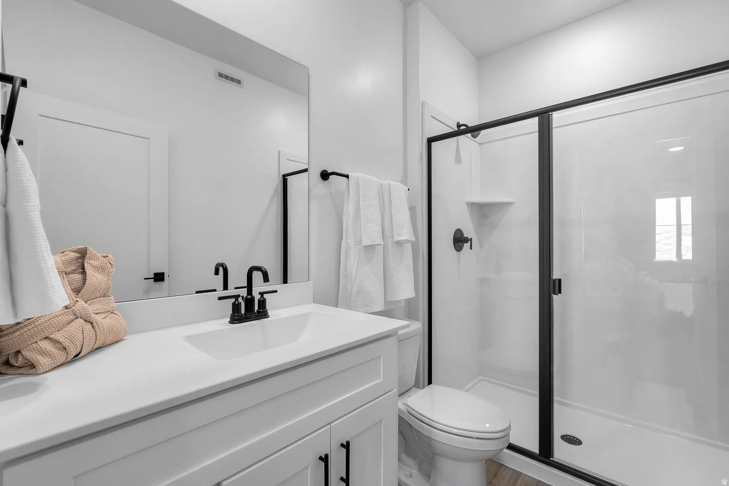 White vanity with integrated sink, black-finish faucet, and coordinating black-frame shower enclosure with a clear glass door