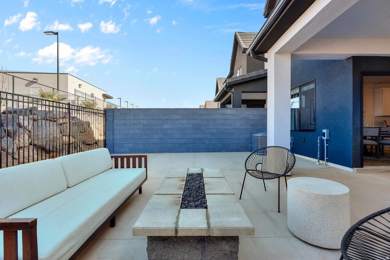 Spacious patio featuring a built-in fire pit, concrete flooring, and a shaded covered area