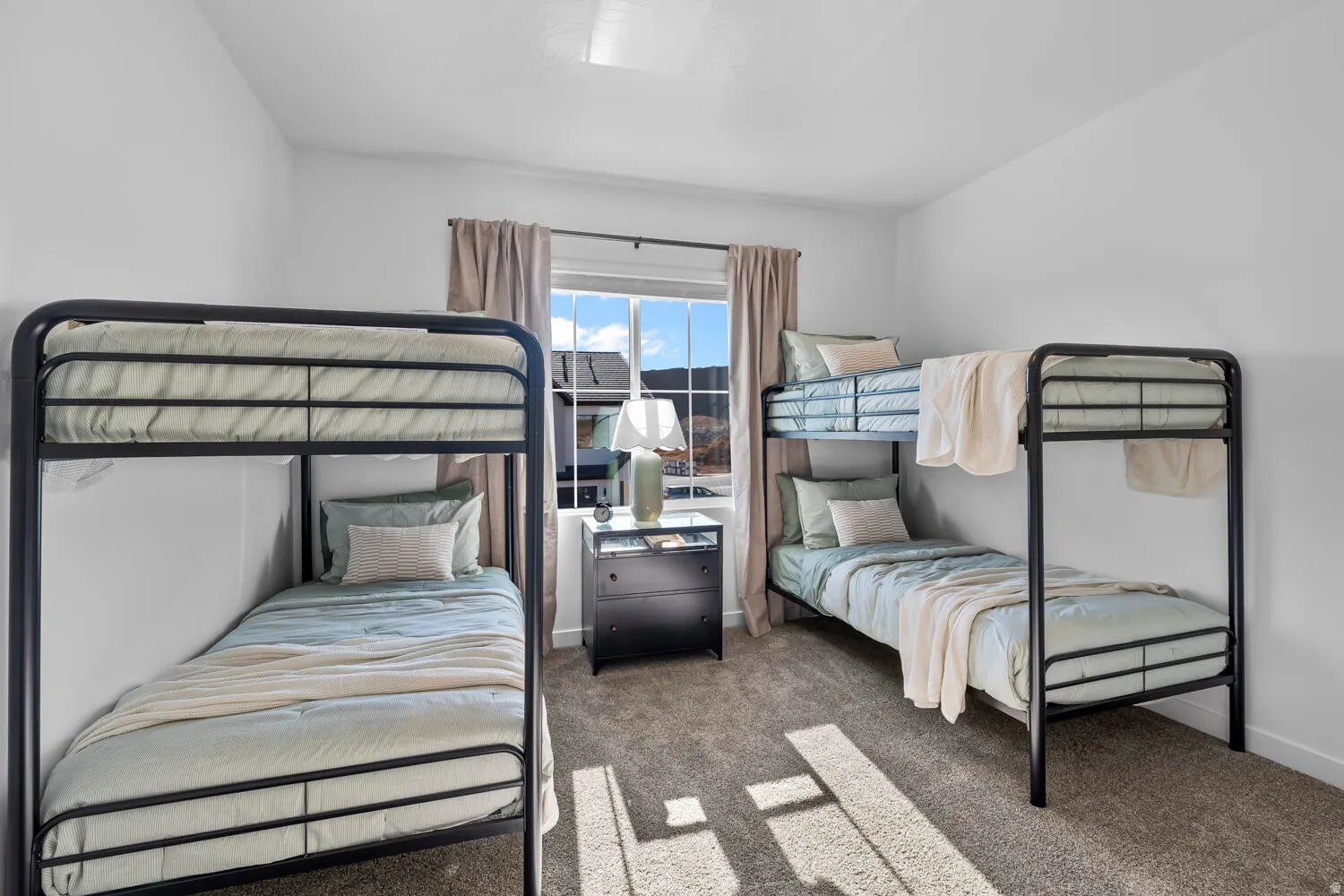 Wall-to-wall carpeting, clean white walls, and a large window with drapes