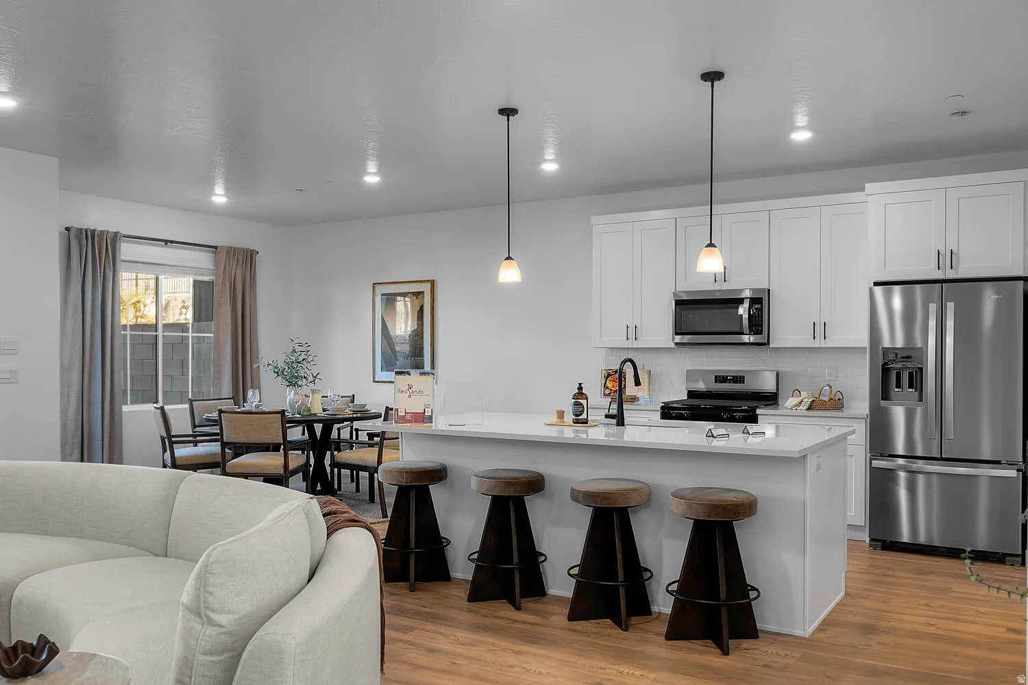 Well-appointed kitchen featuring white cabinetry, stainless steel appliances, and a central island with pendant lighting