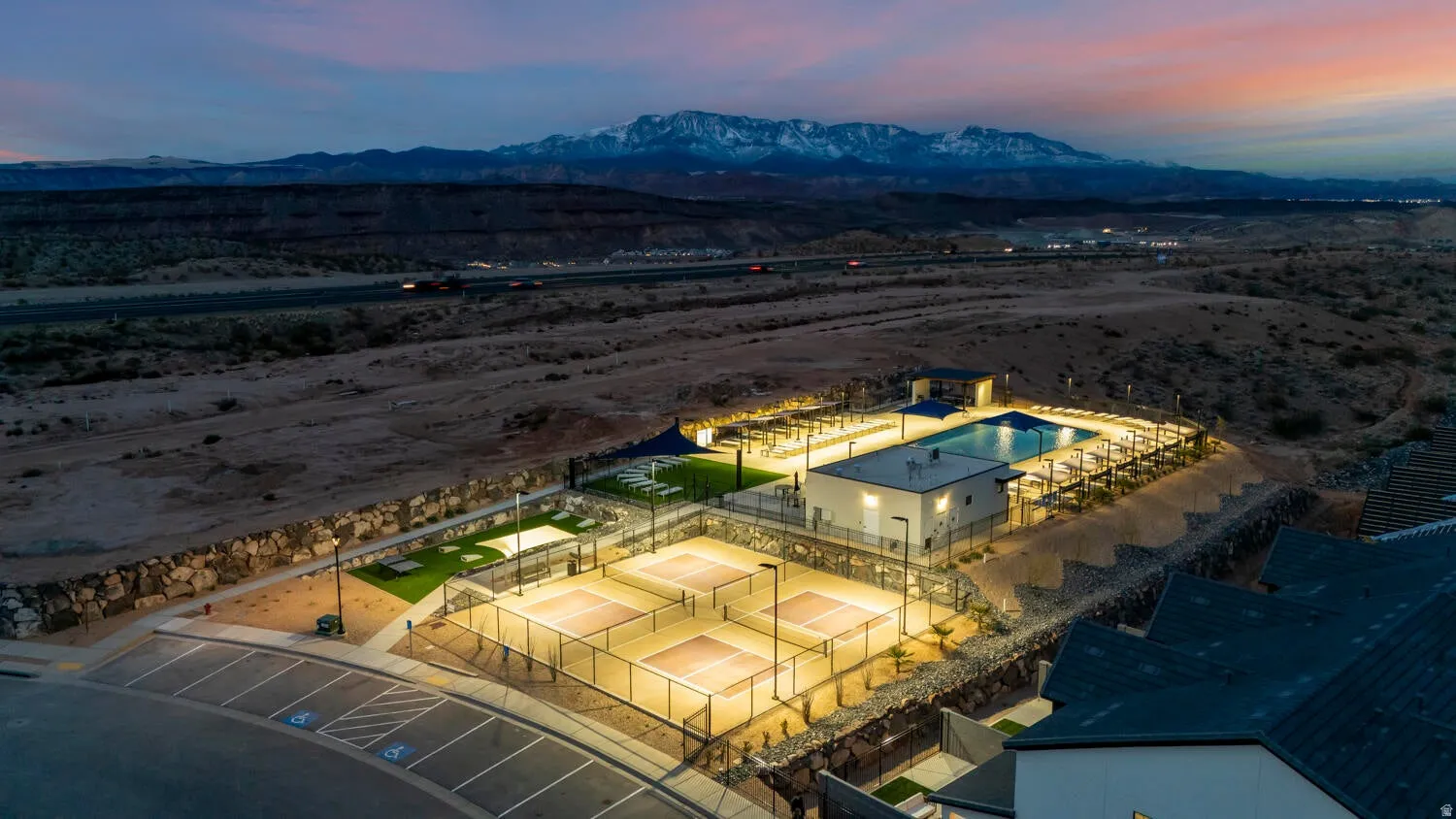 Community amenities featuring multiple illuminated courts, a swimming pool, and dedicated parking