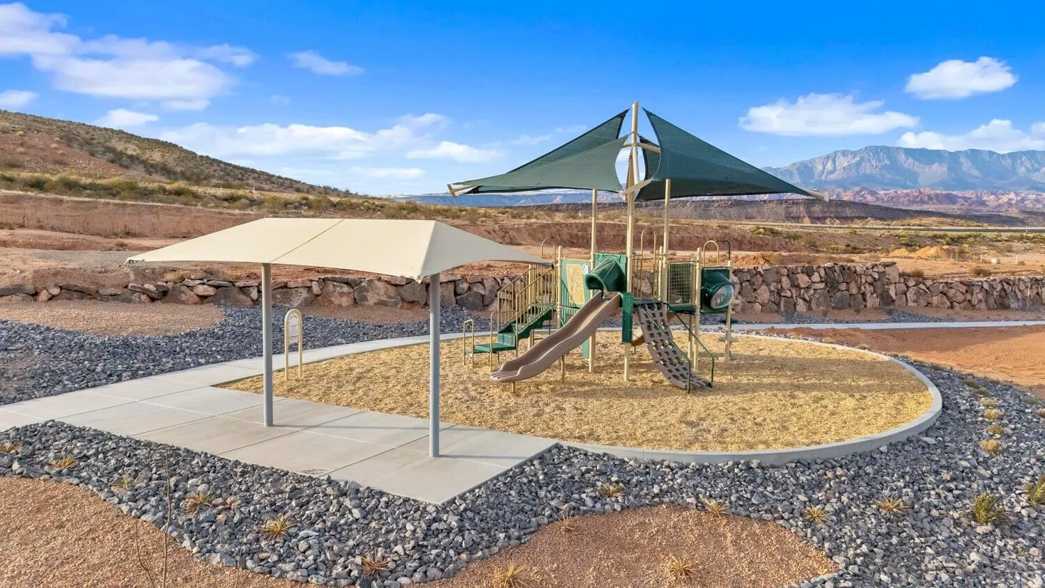 Playground featuring a shade structure, sand ground cover, and a slide