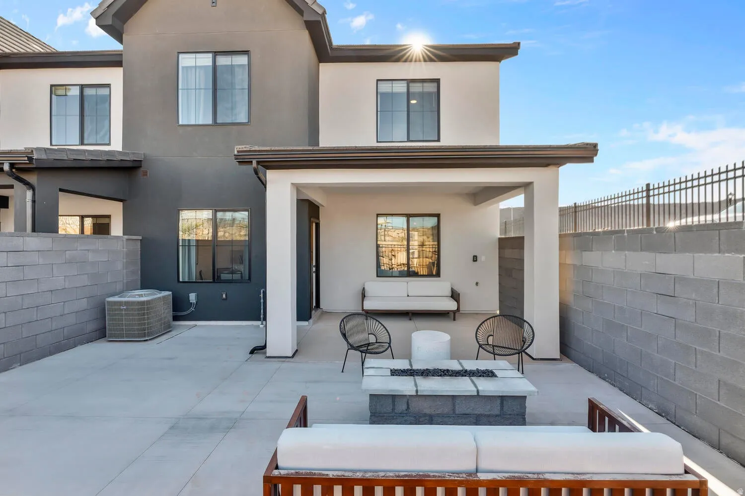 Paved patio area featuring a built-in fire pit, covered outdoor living space, and concrete block privacy walls