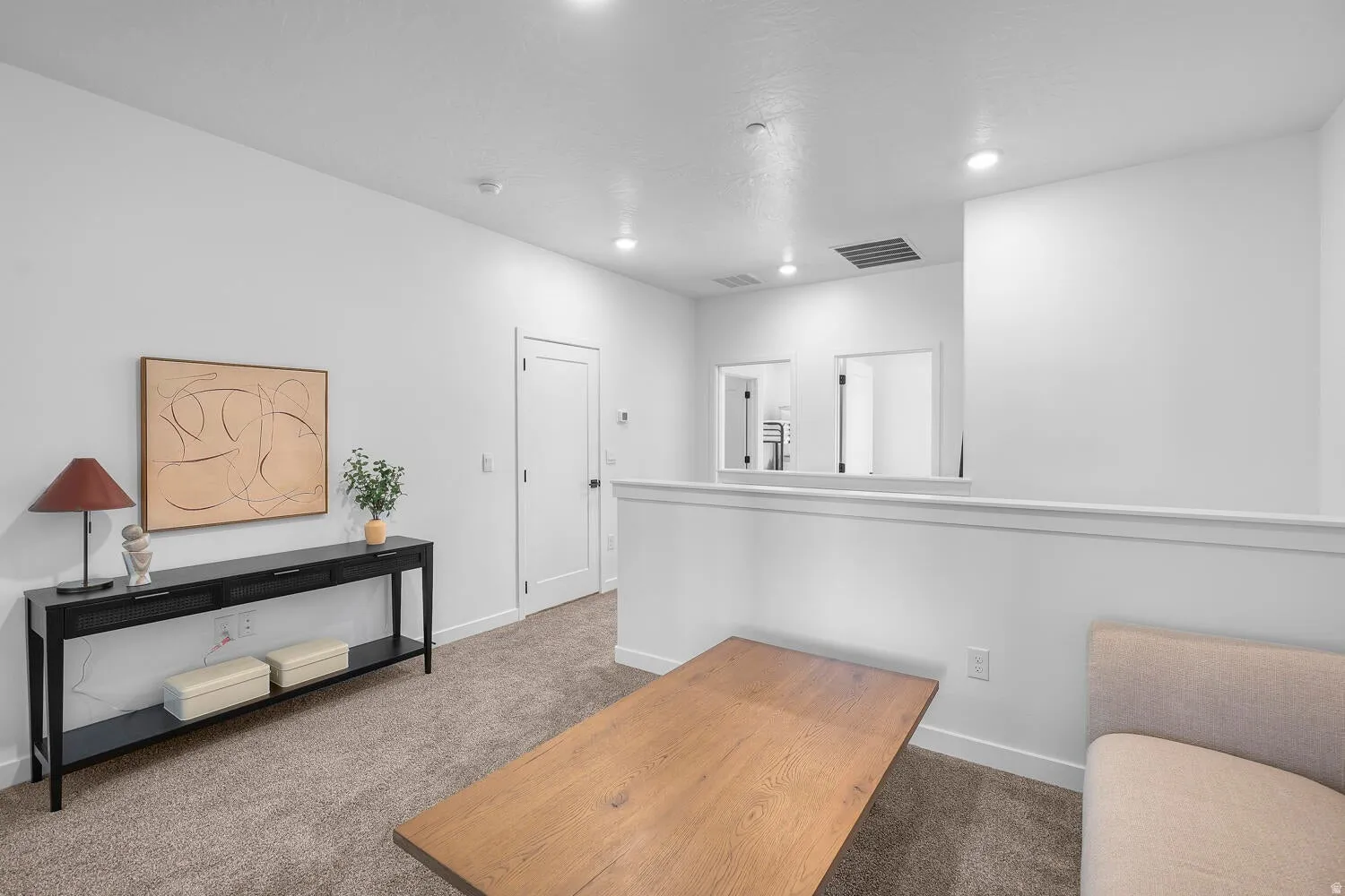 Recessed lighting illuminates the carpeted upper level, featuring an open half-wall design, a solid core door, and a white interior trim package