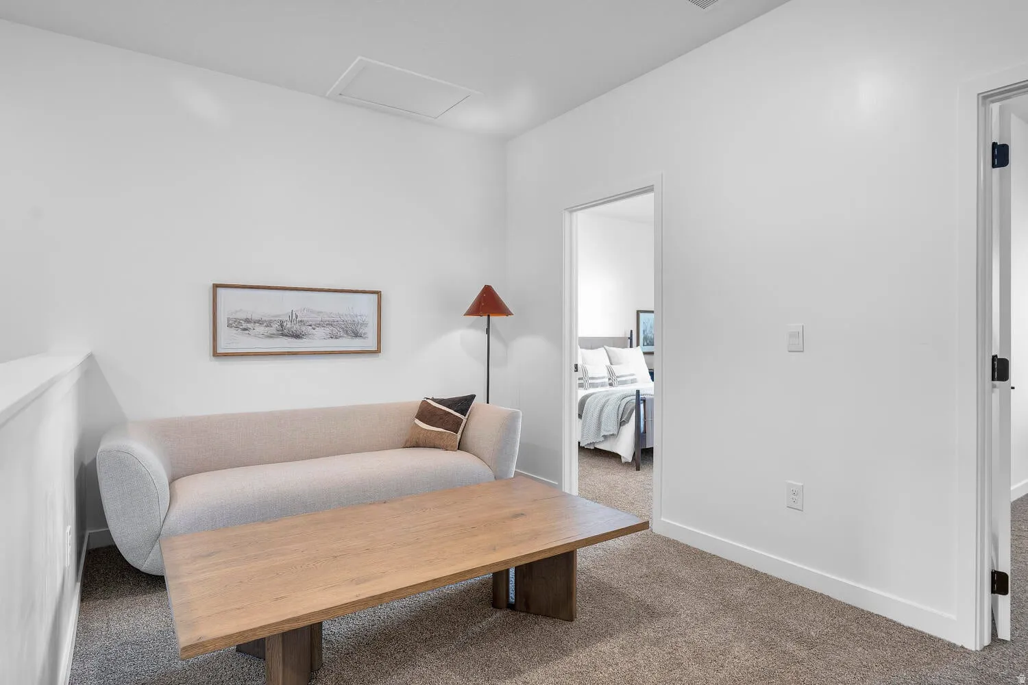 Carpeted landing with a white half-wall, a wood-finish coffee table, and white walls